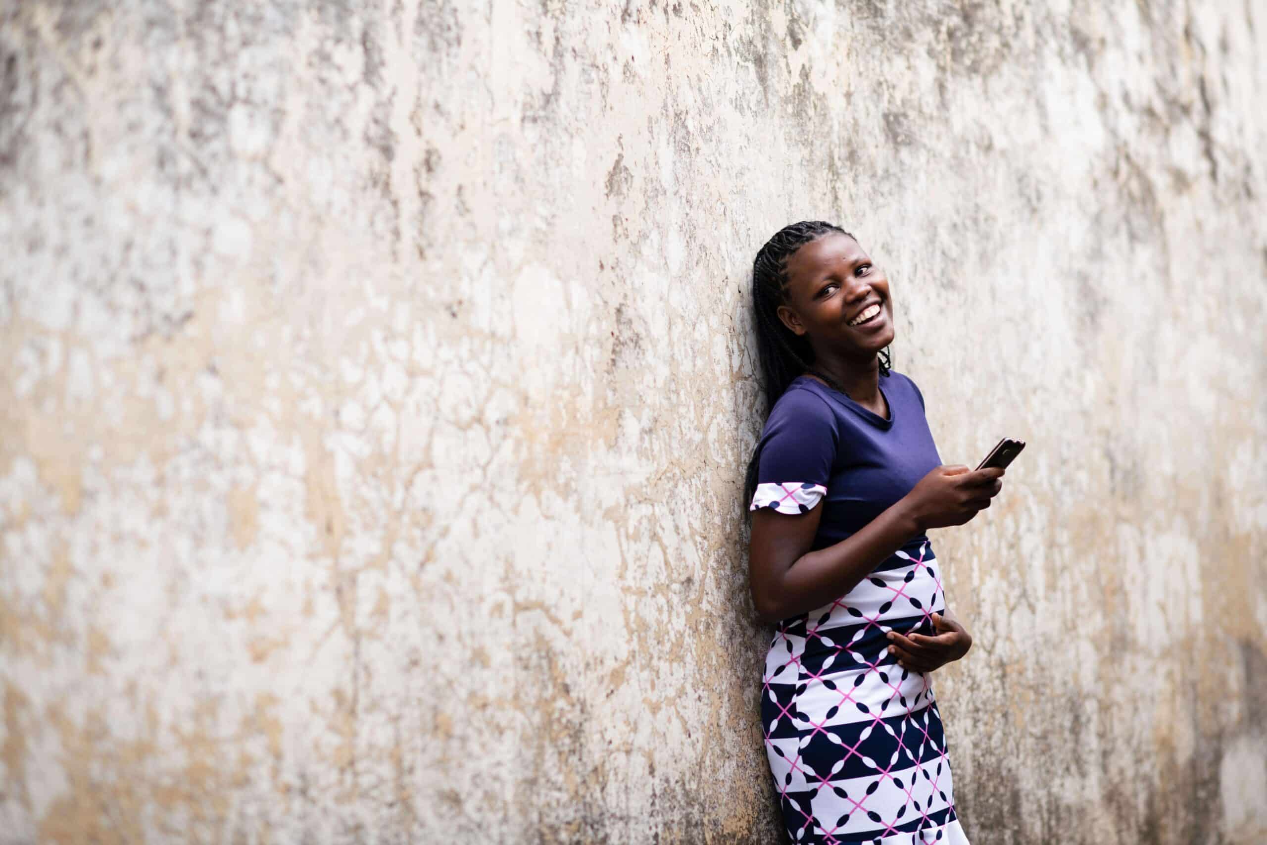 PROMPTS user Monicah Nzembi stands outside her home in Machakos Town, Kenya. She has used PROMPTS to guide her through the early stages of her first pregnancy.